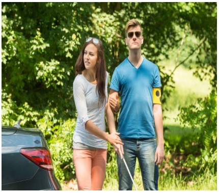 woman leading blind man across road