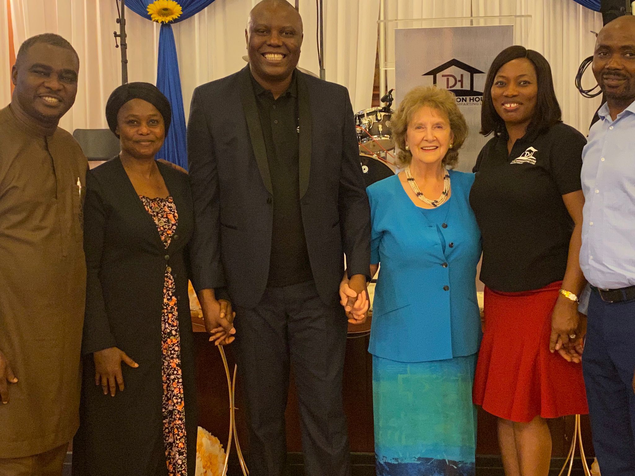 Six smiling people holding hands