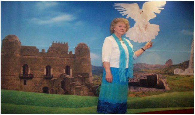 Helen posing against wall painting of holy dove